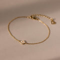 The Rounded Pearl Flower Bracelet features a delicate gold chain with a petite pearl flower charm, making it an elegant choice for everyday wear and perfect for fans of subtle, refined jewelry.