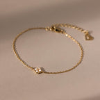 The Rounded Pearl Flower Bracelet features a delicate gold chain with a petite pearl flower charm, making it an elegant choice for everyday wear and perfect for fans of subtle, refined jewelry.