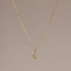 The Rounded Pearl Flower Necklace in 18K Gold features a delicate, four-petal floral pendant accented with white stones—ideal for lovers of subtle, feminine jewelry. Shown on a neutral background.