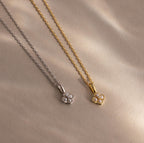 Two elegant Rounded Pearl Flower Necklaces—one in silver and one in gold—each feature a delicate pearl flower pendant, gracefully presented on a beige background.
