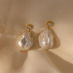 Diamond Baroque Pearl Studs in 18K Gold featuring large baroque pearls and sparkling diamonds are showcased on cream-colored fabric.