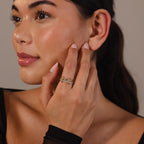 A woman with smooth skin wears the Pave Mixed Metal Linked Ring Set, gently touching her face and gazing to the side with a slight smile.