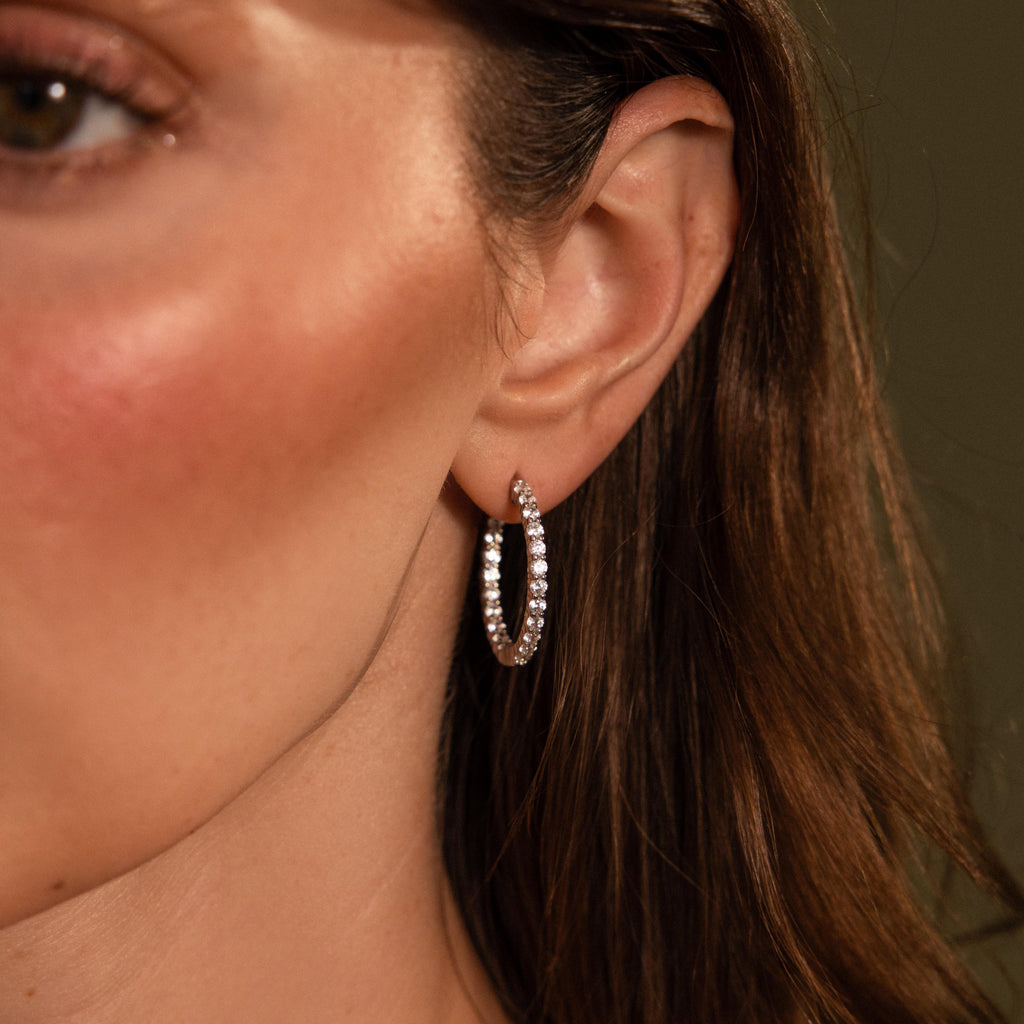 Close-up of a woman's ear wearing sparkling, rhinestone-studded Inside Out Diamond Hoops in Silver for a touch of elegance.