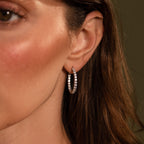 Close-up of a woman's ear wearing sparkling, rhinestone-studded Inside Out Diamond Hoops in Silver for a touch of elegance.