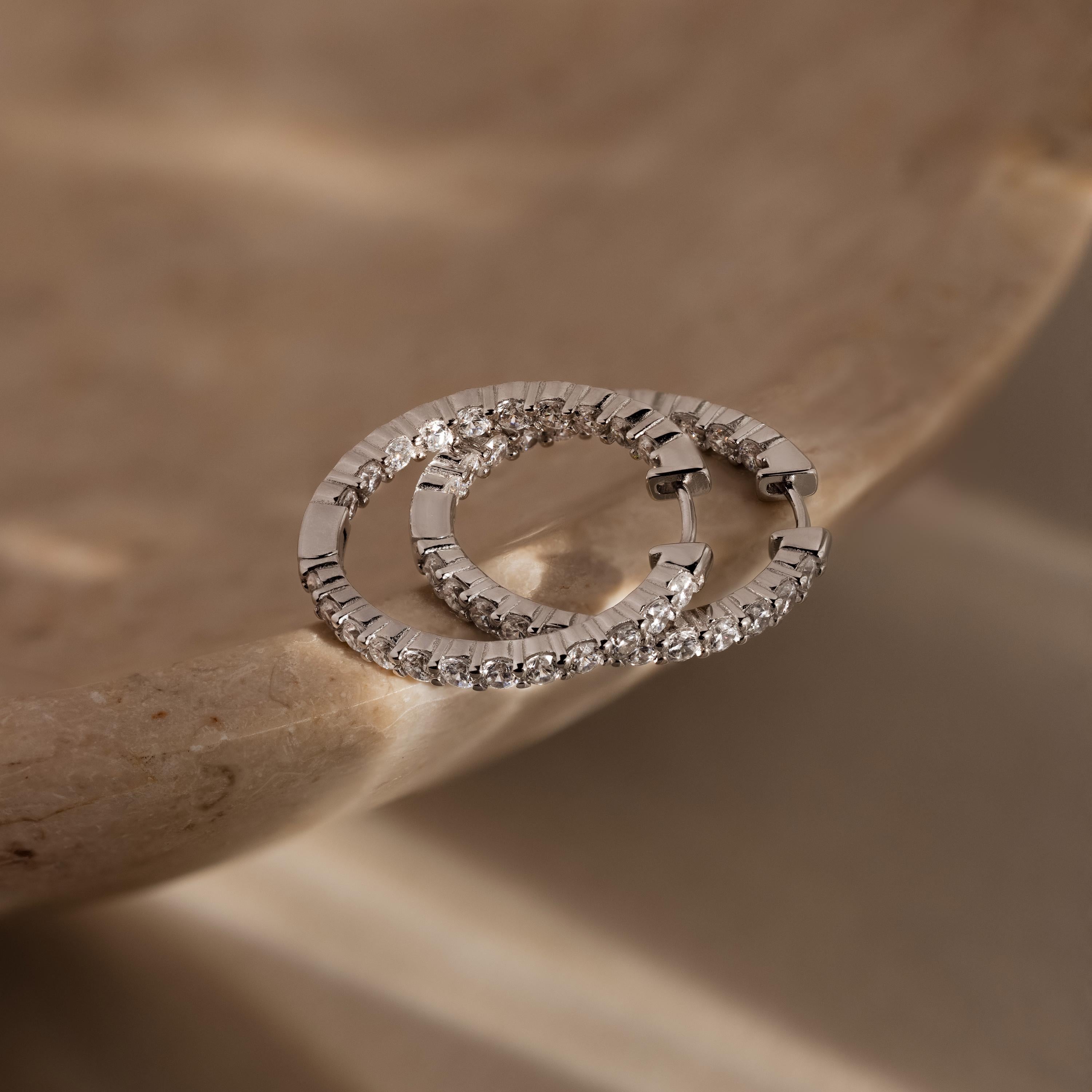 Inside Out Diamond Hoops in Silver displayed on a smooth, beige marble surface.