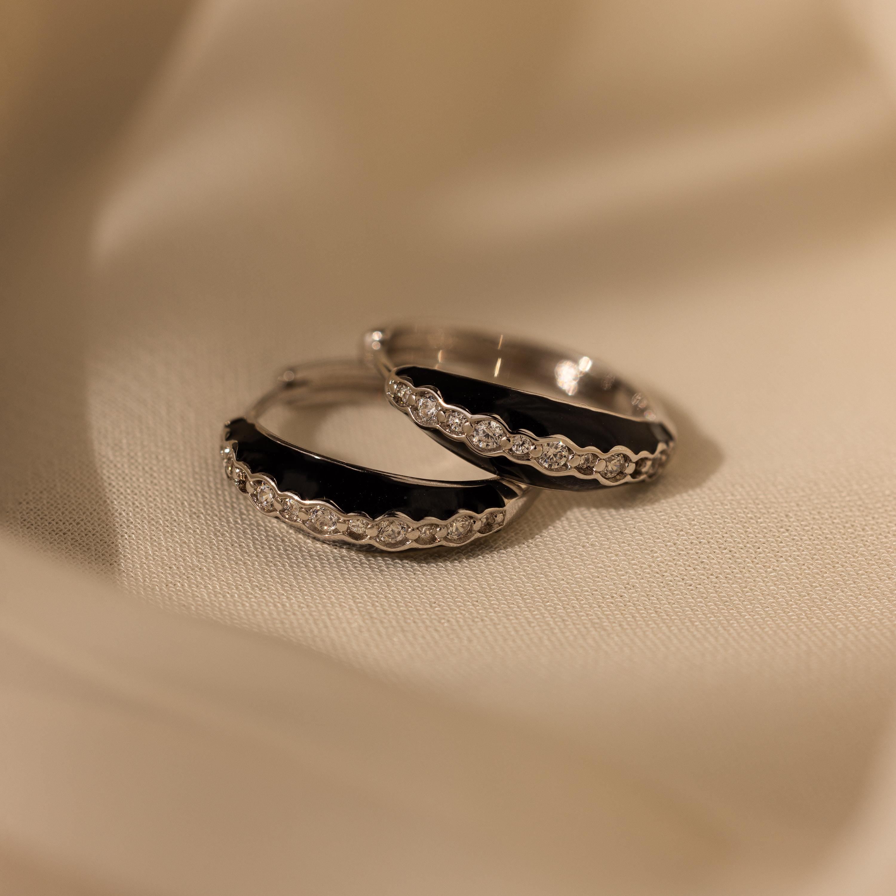 Noir Pave Dome Hoops featuring enamel black accents and clear gemstone pave, displayed on a soft beige fabric background.