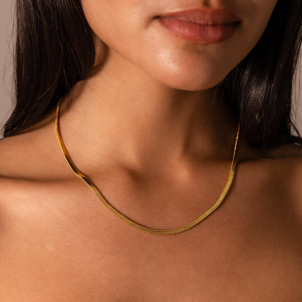 Woman wearing the Bold Snake Chain Necklace, shown from the shoulders up with focus on her neck and collarbone—a modern jewelry essential.
