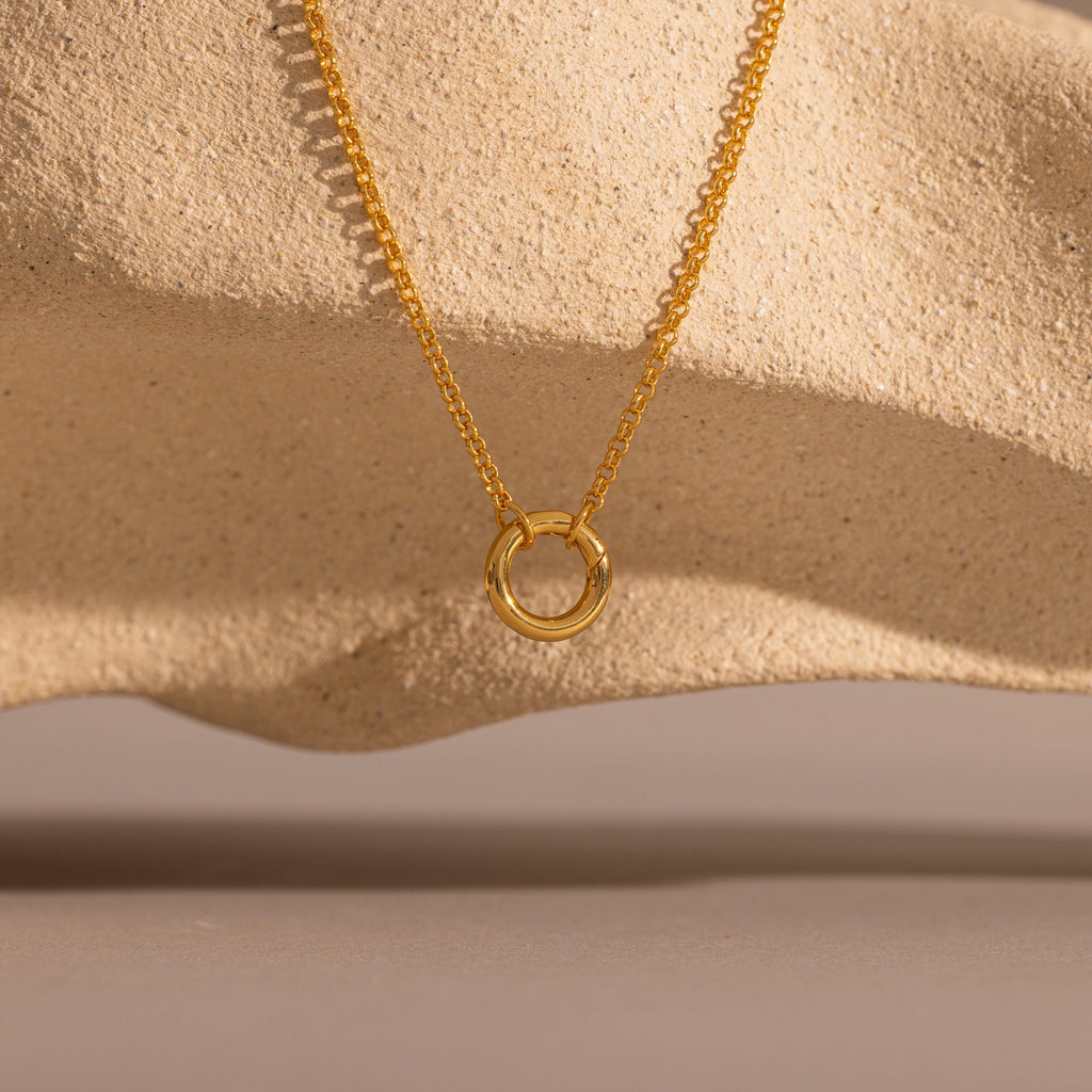Cable Circle Charm Necklace shown on textured beige stone with soft shadows; a versatile piece ideal for layering and adding effortless elegance to any look.