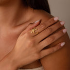 Woman with light pink nails wears the Open Duo Starfish Ring, a gold coastal-inspired statement piece, on her finger as her hand rests on her shoulder.