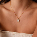 Close-up of a woman in a white top wearing the Square Mother of Pearl Necklace, with a delicate gold chain and an iridescent square pendant.