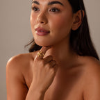 A woman with long dark hair poses thoughtfully with her hand on her chin, wearing the Open Duo Starfish Ring inspired by coastal style.
