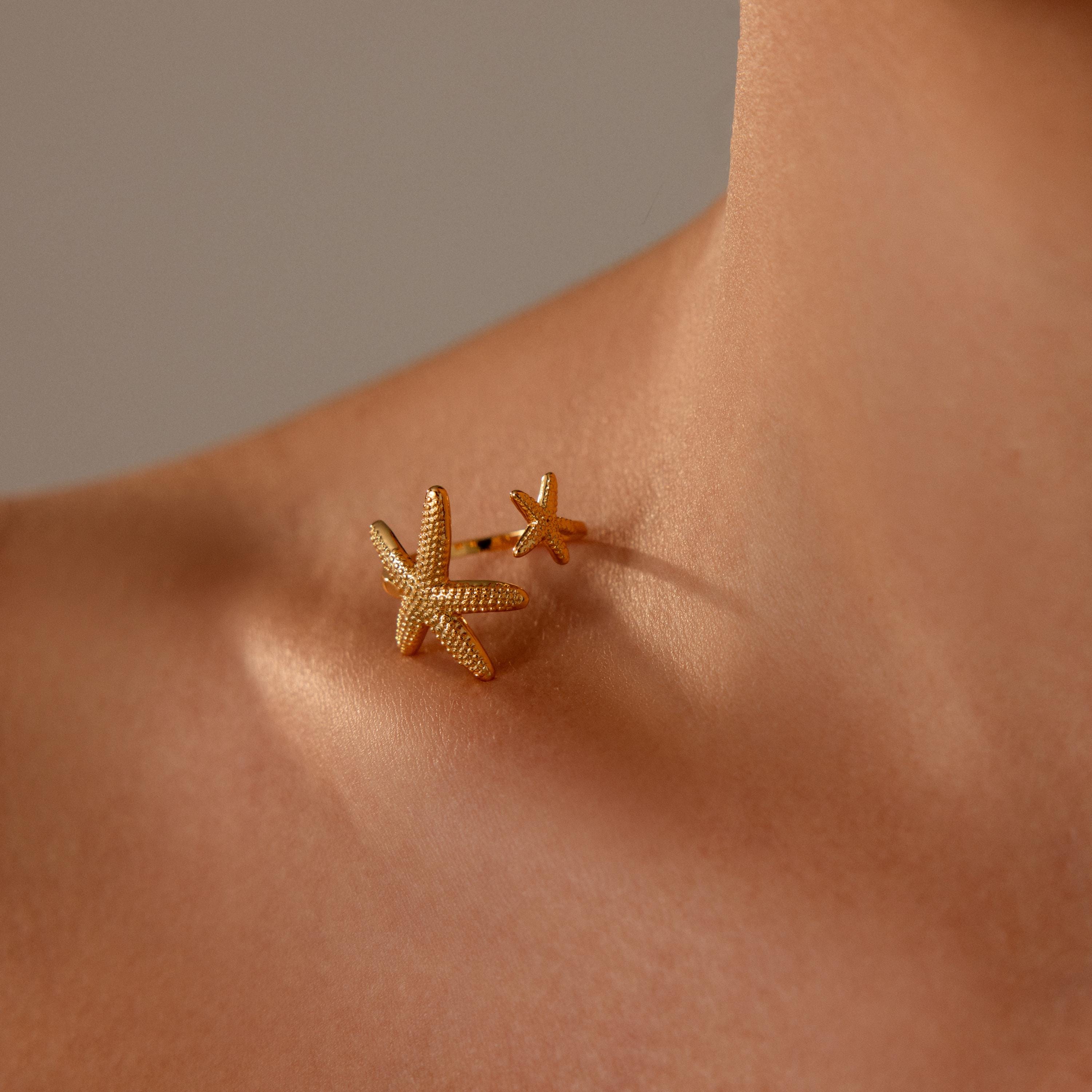 Open Duo Starfish Ring on a persons finger near their collarbone—a striking statement piece with coastal-inspired charm.