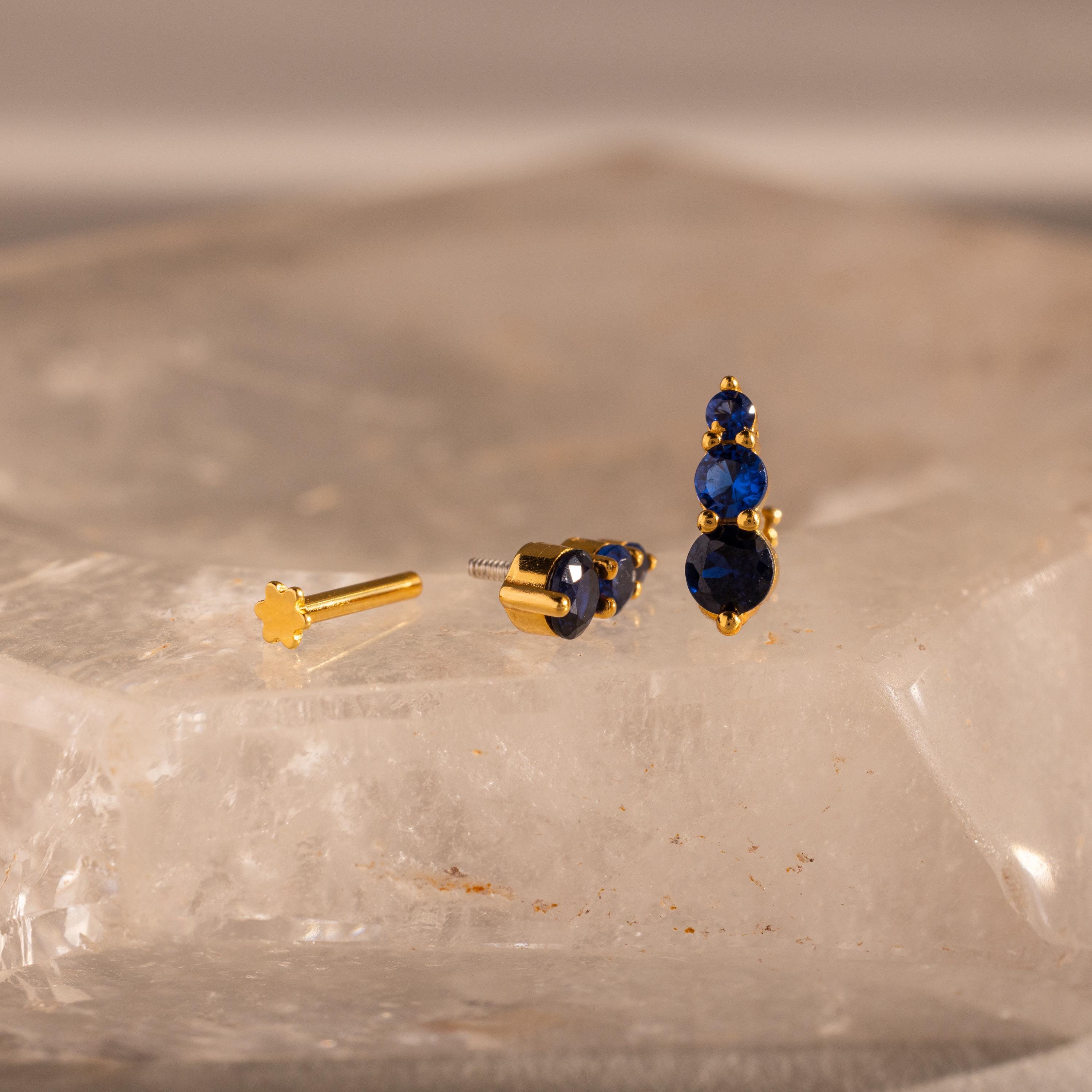 Ombre Birthstone Flatback Studs feature three blue gems on a clear, textured surface—ideal as a personalized gift or unique studs for any occasion.
