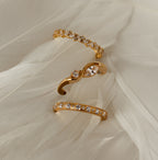 The Diamond Cluster Eternity Ring with sparkling gemstones and a clustered design is displayed on a soft, cream-colored feather background.