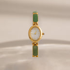 Our Jade Band Timepiece with a white dial and green jade rectangular inlay stones on the bracelet, centered against a soft beige background.