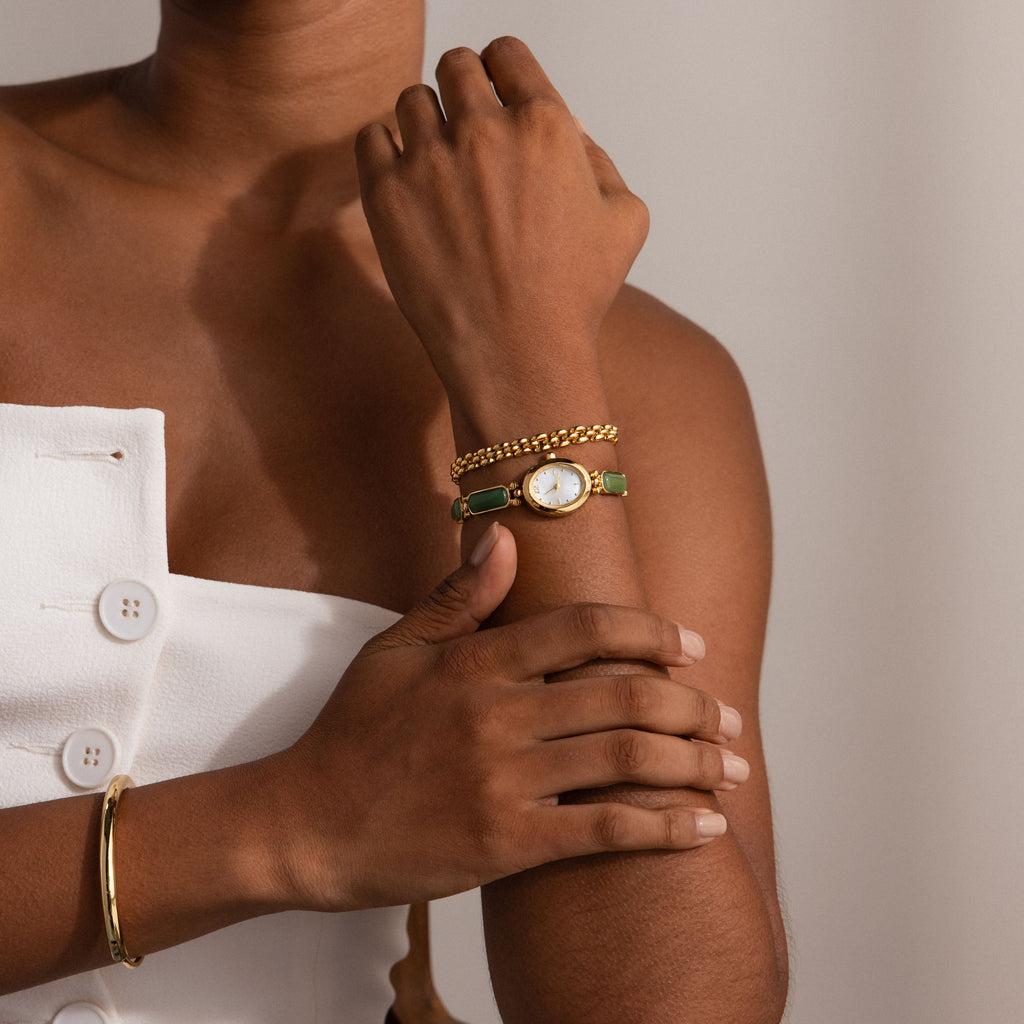 A model wearing our Jade Band Timepiece styled with a gold link bracelet and gold bangle.