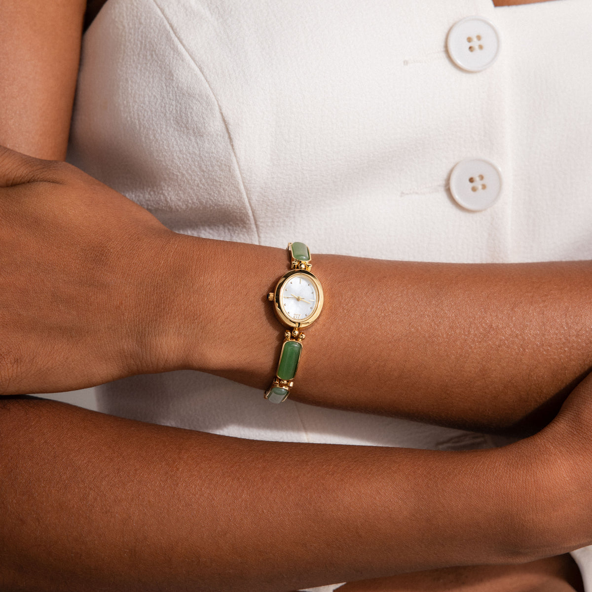 Our Jade Band Timepiece worn on a woman's wrist over a white button-up top.