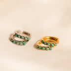 Close up of our Garden Green Opal Huggie earrings in silver and gold on a beige fabric background