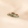 Close up of our Garden Green Opal Huggies in silver on a beige fabric background