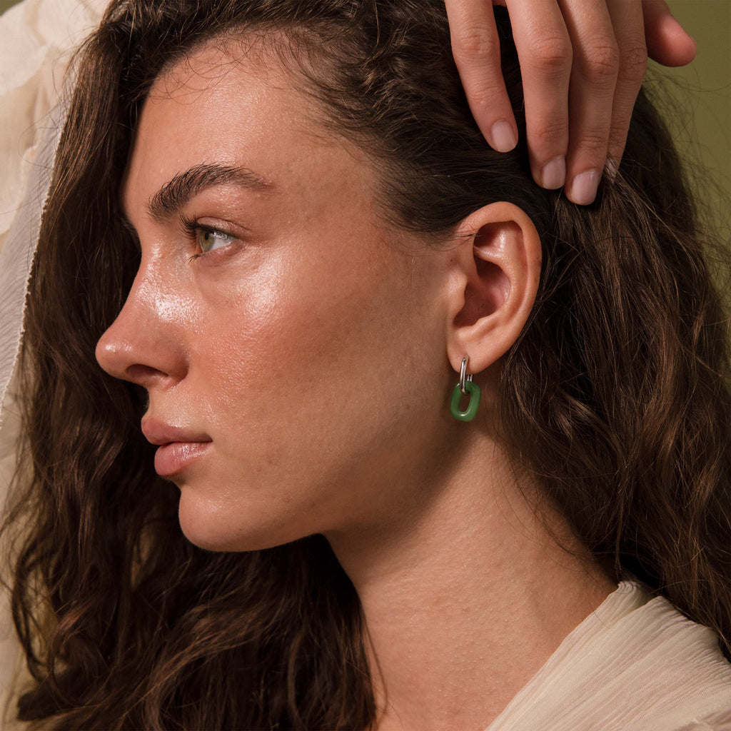 Woman wearing a single Jade Link Drop Hoop earring with a sleek silver chain.