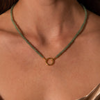 Close-up of the Beaded Jade Clasp Necklace in 18K Gold, featuring green jade beads and a gold circular pendant, elegantly layered on a woman's neck.