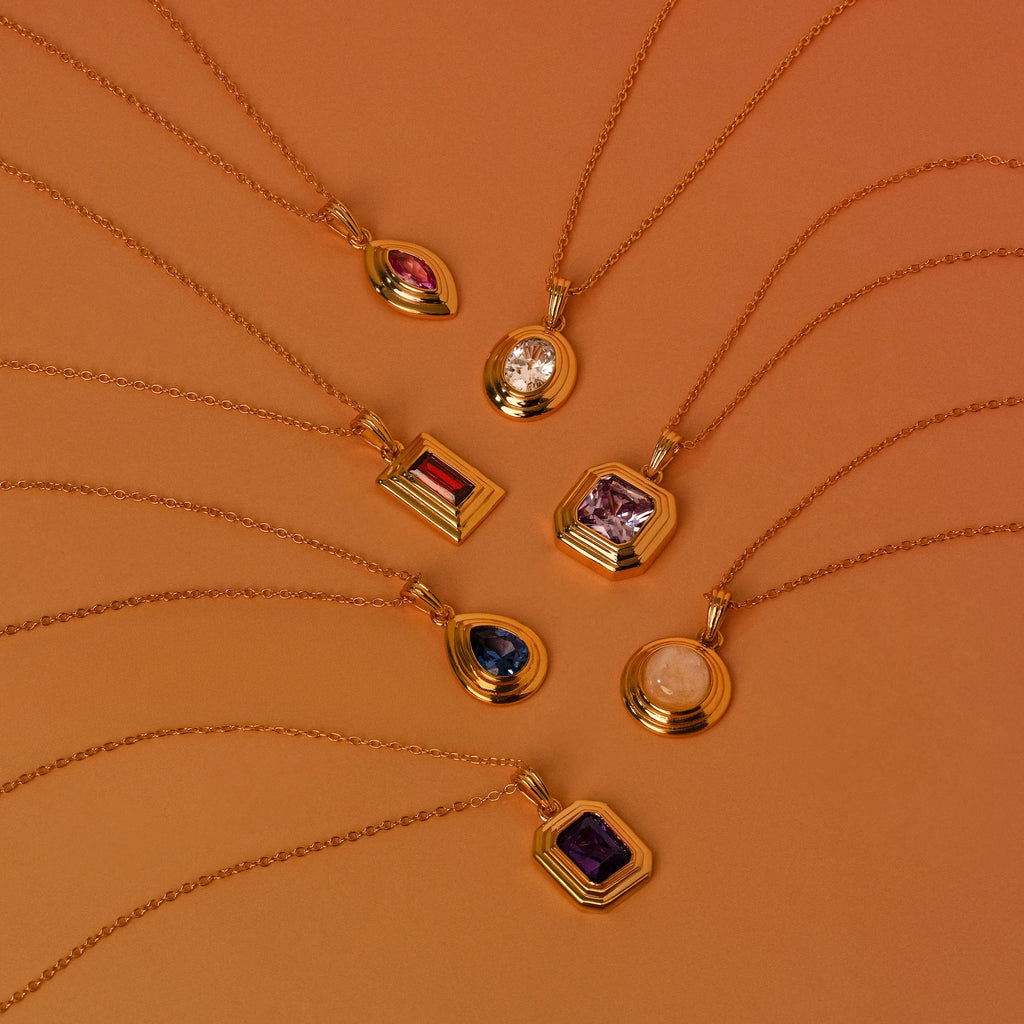 Eight Ribbed Peridot Pendant Necklaces are arranged in a fan shape on a warm brown background.