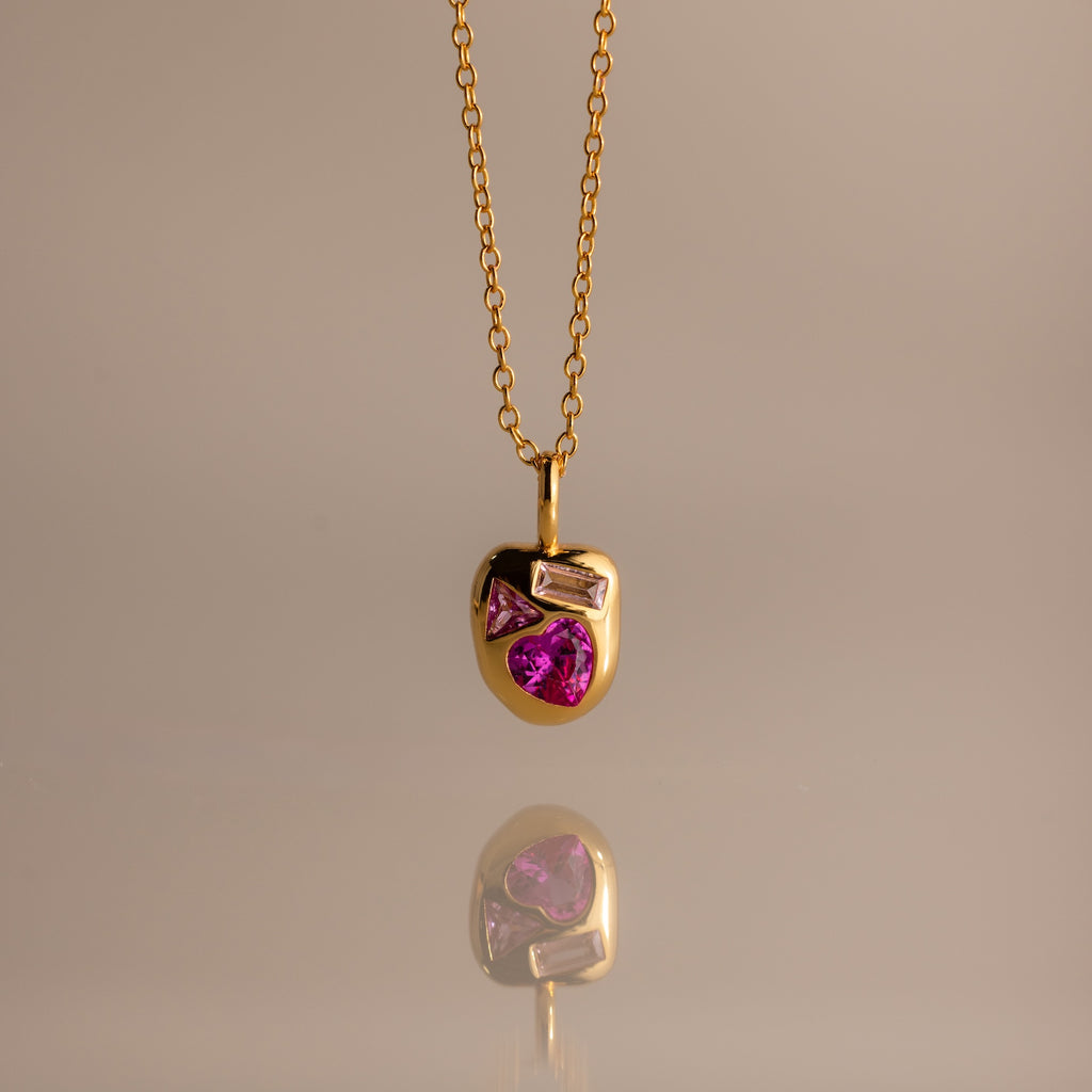 The Mixed Pink Tourmaline Capsule Necklace features pink and clear gemstones set in gold, shown against a neutral background.