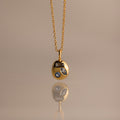 Mixed Aquamarine Capsule Pendant Necklace featuring a round charm with three different shapes of aquamarine gemstones, displayed on a beige background.