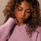 Woman with curly hair wearing a lavender sweater and a Mixed Amethyst Capsule Pendant Necklace, eyes closed and hand near her chin.