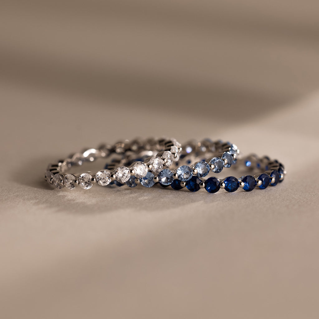 The Lace Eternity Aquamarine Ring features shimmering blue stones, evoking timeless elegance. Perfect for stacking or wearing solo as a statement birthstone ring, it stands out beautifully against any background.