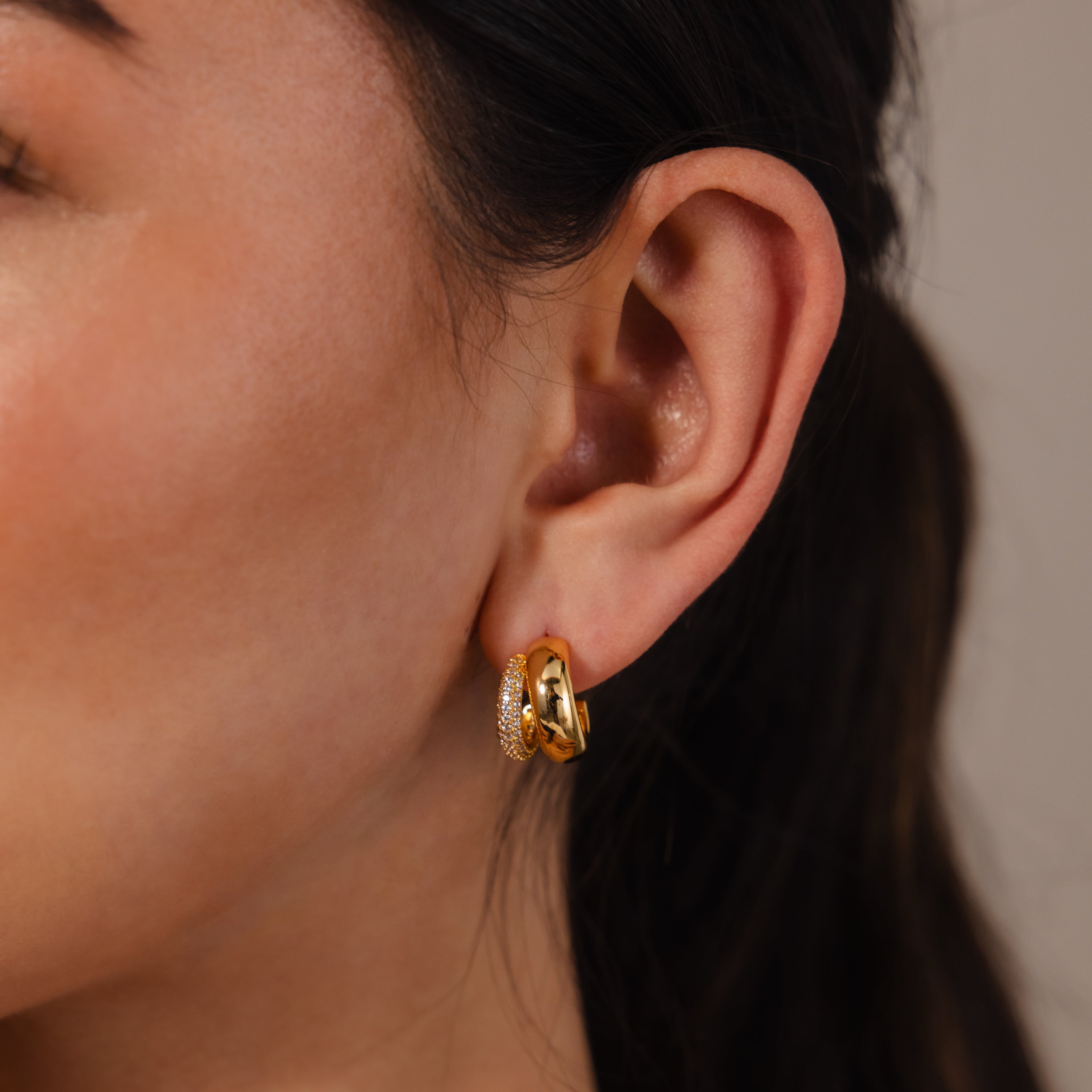 A close-up of a woman's ear adorned with Duo Pave Dome Studs in 18K Gold, adding a sparkling touch to her everyday jewelry look.