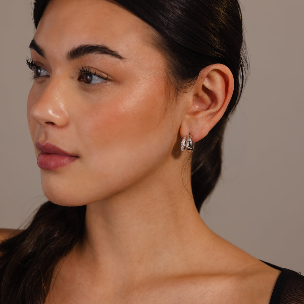 Woman with smooth skin and dark hair wears Duo Pave Dome Studs in White Gold—perfect everyday jewelry—looking to the left against a plain background.