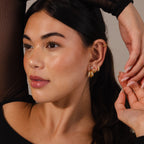 Woman with long dark hair wearing Duo Pave Dome Studs in Mixed Metal, a black top, and posing with arm raised—perfect everyday jewelry to add elegance with their mixed metal pavé curve design.