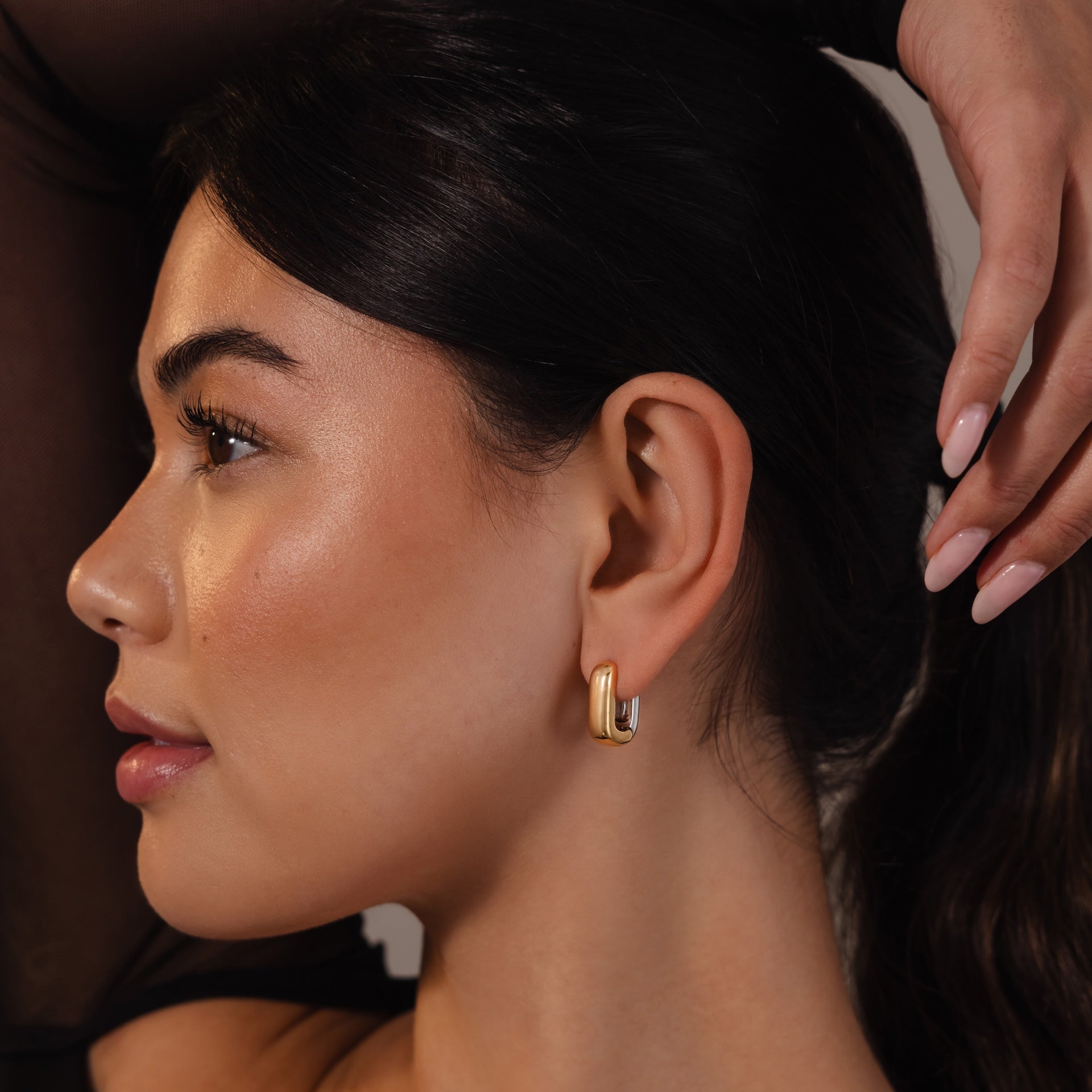 A woman with smooth skin and dark hair wears Bold Link Hoops, gazing to the side with a calm expression—showcasing this modern jewelry style.