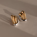 Mixed Metal Raindrop Studs feature gold and silver abstract sculptural earrings with a curved design, adding a modern touch to any look.