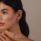 A woman with dark hair wears modern Eclipse Dome Studs in White Gold, gazing to the side with her hand near her chin.