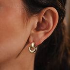 Close-up of a woman's ear wearing Eclipse Dome Studs in 18K Gold, highlighting the modern elegance and shiny finish of these contemporary stud earrings.