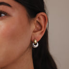 A close-up of a woman's ear adorned with Eclipse Dome Studs, featuring sculptural two-tone gold and silver hoops that highlight a modern jewelry style.