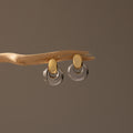 Eclipse Dome Studs in Mixed Metal are displayed on a curved wooden branch against a neutral background, highlighting their sculptural design and modern jewelry aesthetic.