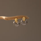 Eclipse Dome Studs in Mixed Metal are displayed on a curved wooden branch against a neutral background, highlighting their sculptural design and modern jewelry aesthetic.