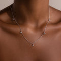 The Diamond Station Necklace in Silver features small round diamond pendants that elegantly accentuate a womans neck and collarbone with modern sophistication.