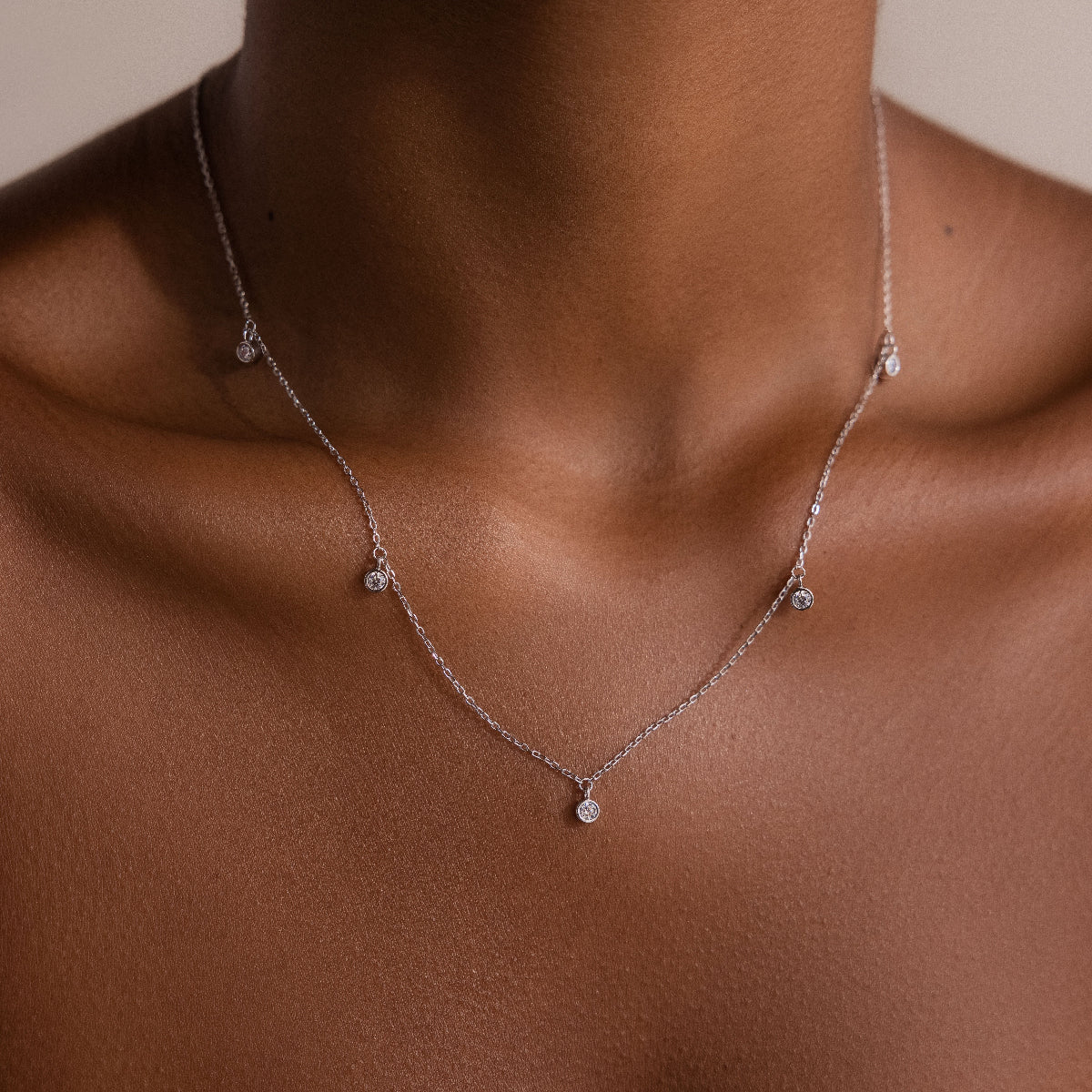 The Diamond Station Necklace in Silver features small round diamond pendants that elegantly accentuate a womans neck and collarbone with modern sophistication.