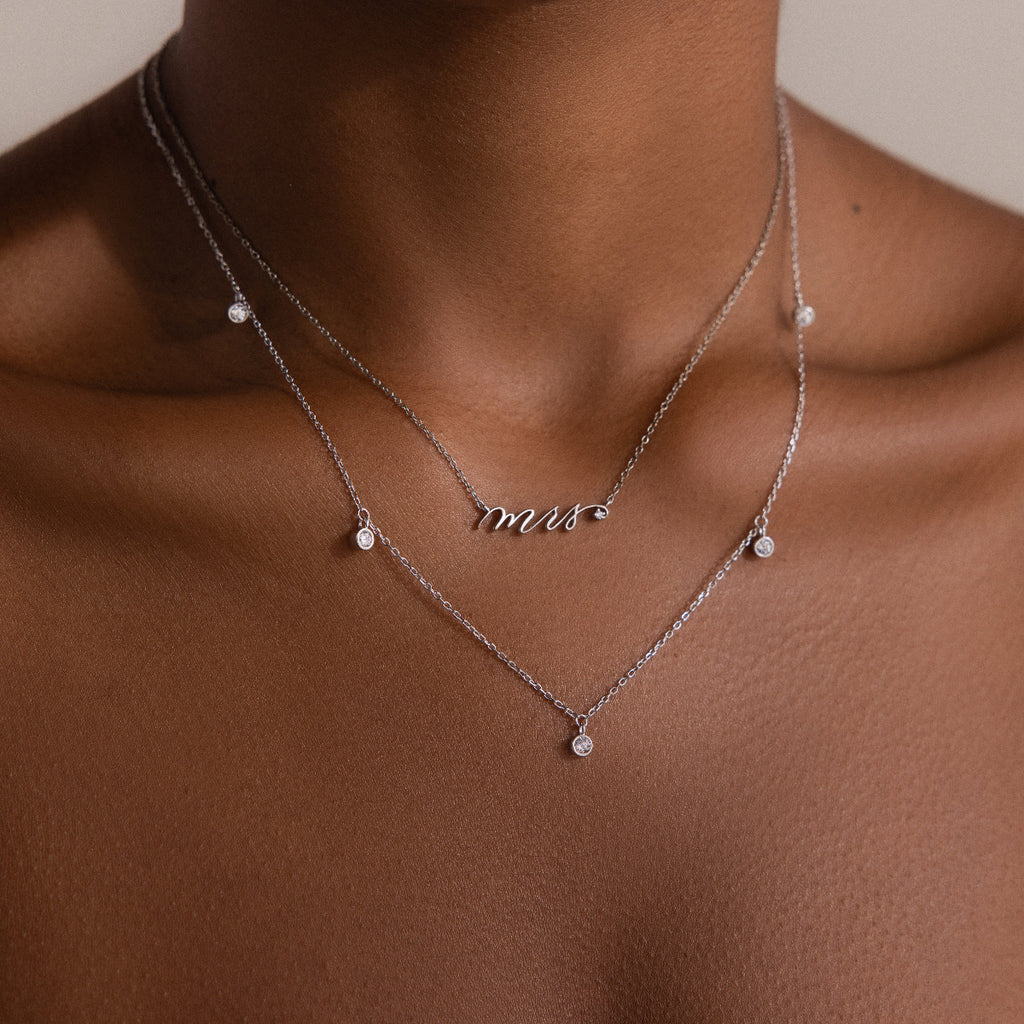 Close-up of a Diamond Station Necklace in Silver on a persons neck, featuring small round pendants—a timeless accessory that brings modern elegance to any outfit.