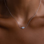 The Opal Eye Necklace in Silver features a delicate oval eye pendant resting gracefully on the neck, serving as a subtle and lucky talisman.