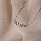 The Mrs. Necklace in Silver, shown on a soft beige fabric, makes an ideal wedding gift for any bride-to-be.