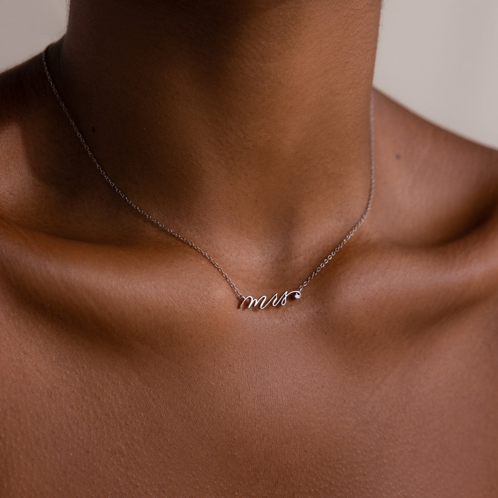 A close-up of the Mrs. Necklace in Silver on a neck, featuring a cursive mrs pendant—an ideal wedding gift for any bride-to-be.