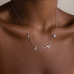 The Mama Letter Necklace in Silver spells MAMA and rests elegantly on the neck and collarbone, celebrating motherhood against a neutral background.