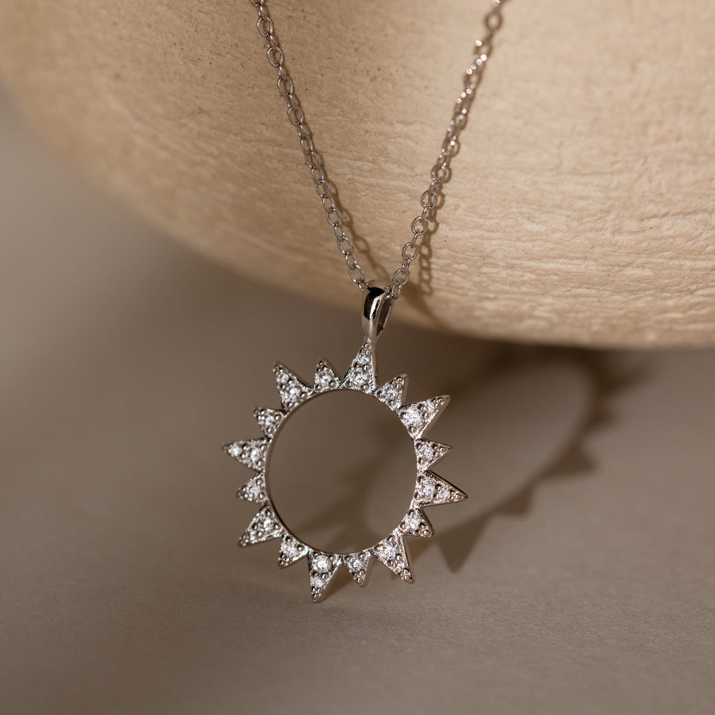 The Pave Sun Necklace in Silver features sparkling diamonds and pave accents on a delicate chain, displayed against a neutral background.