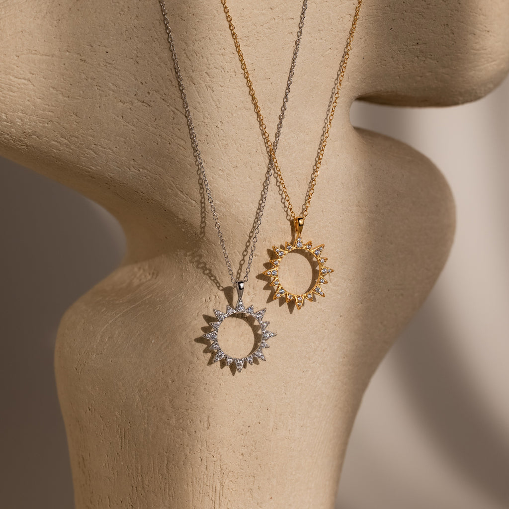 The Pave Sun Necklace in Silver and Gold is displayed on a beige sculpted stand.