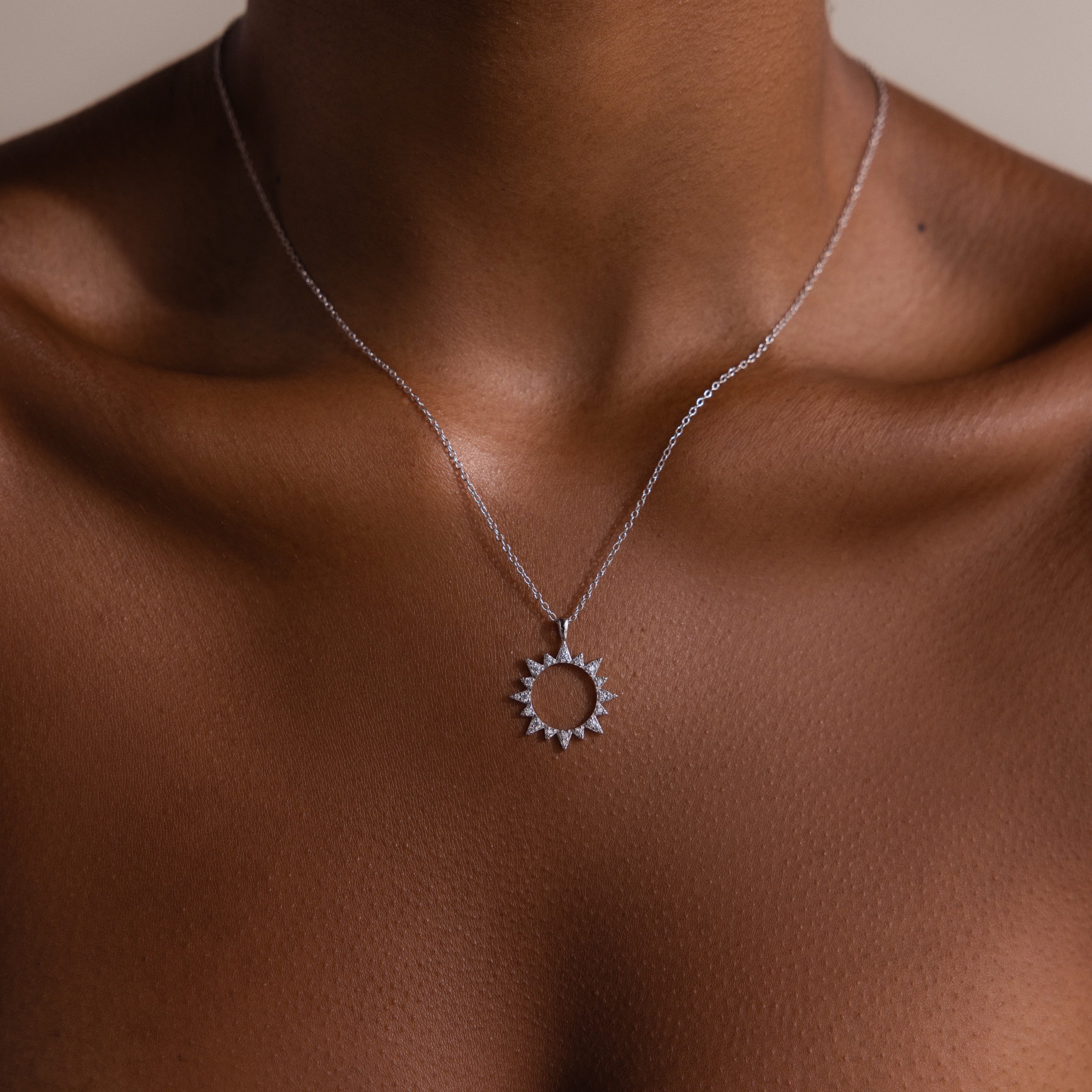 The Pave Sun Necklace in Silver features sparkling pave accents, resting on the neck and upper chest and shimmering against a neutral background.